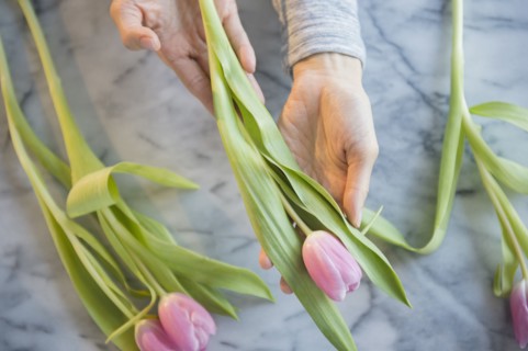 Mixed race woman holding tulips at table