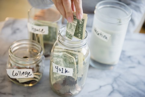 Mixed race woman saving money in jars