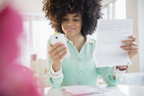 Mixed race woman paying bill with cell phone