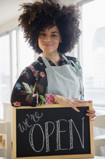 Mixed race woman holding open sign in cafe