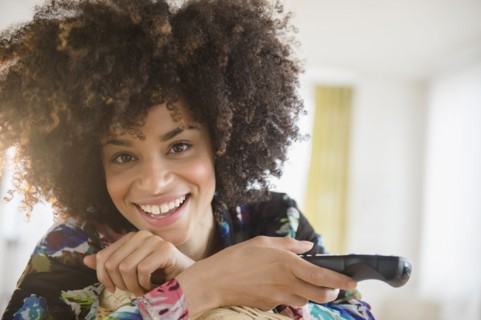 Mixed race woman holding television remote control