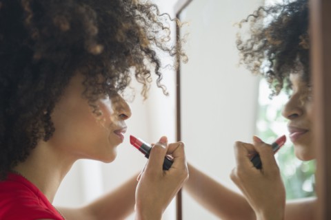 Mixed race woman applying lipstick in mirror