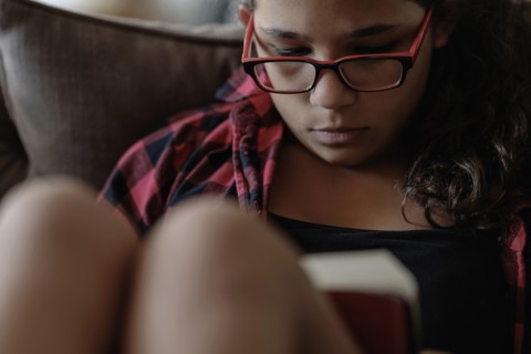 Mixed race girl reading on sofa