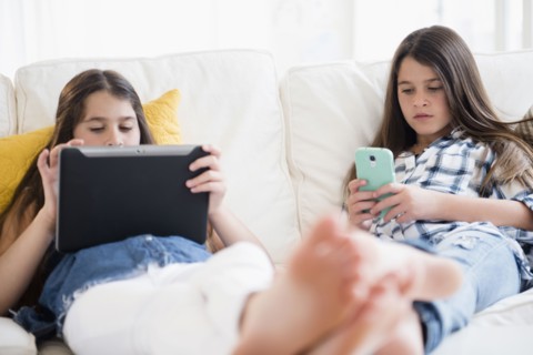 Caucasian twin sisters using technology