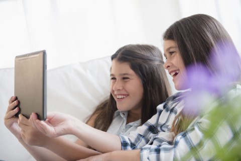 Caucasian twin sisters using digital tablet