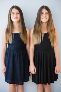 Caucasian twin sisters wearing dresses