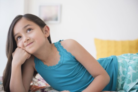 Smiling girl daydreaming with chin in hand