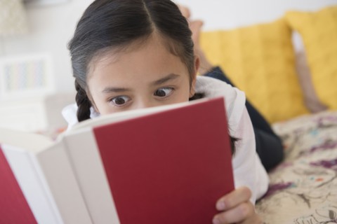 Girl reading book on bed