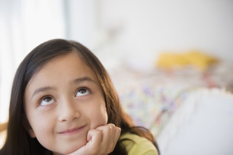 Smiling girl daydreaming with hand on chin