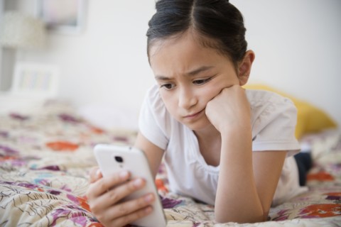Frustrated girl using cell phone on bed
