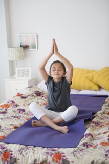 Girl practicing yoga on bed