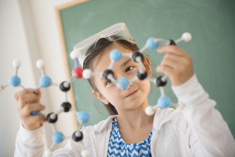 Girl examining molecular model in science class
