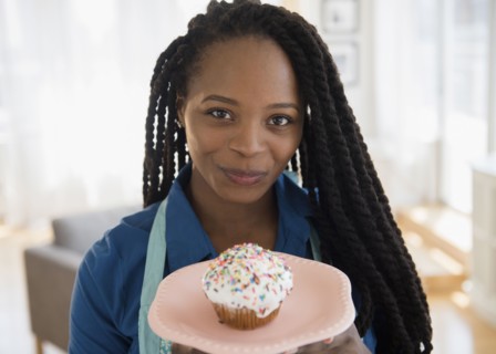 Black woman holding cupcake on plate