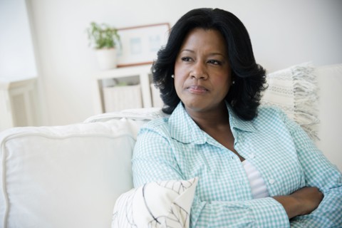 Unhappy Black woman sitting on sofa