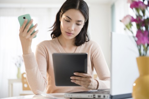 Hispanic woman using cell phone and digital tablet