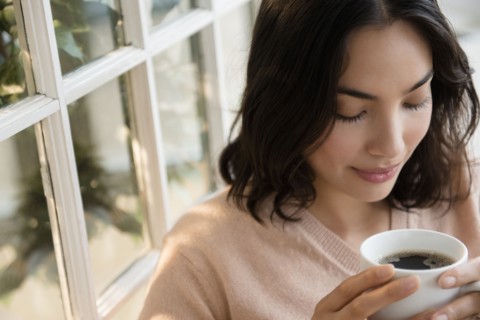 Hispanic woman drinking cup of coffee