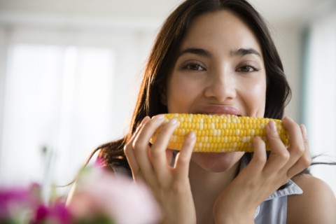 Hispanic woman eating corn on the cob