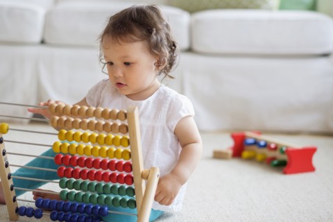 Mixed race baby girl playing with abacus
