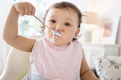 Mixed race baby girl eating yogurt