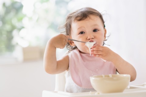 Mixed race baby girl eating yogurt