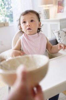 Mother feeding baby daughter in high chair