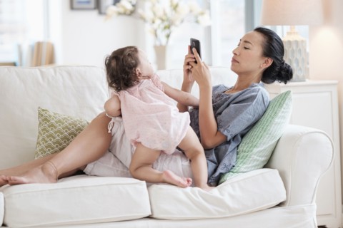 Mother photographing baby daughter