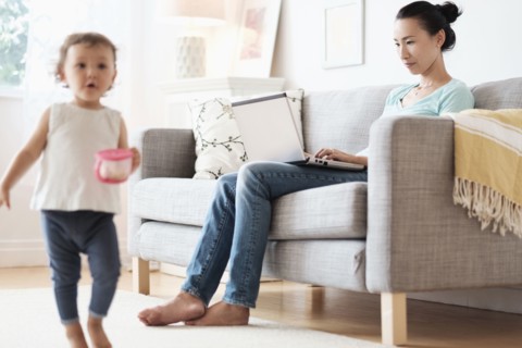 Mother using laptop ignoring baby daughter