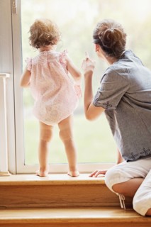 Mother and baby daughter looking out window