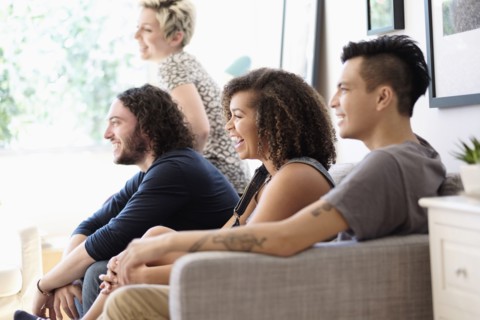 Friends watching television on sofa