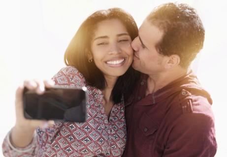 Hispanic couple taking selfie outdoors