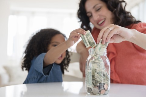 Mother and daughter saving money in jar