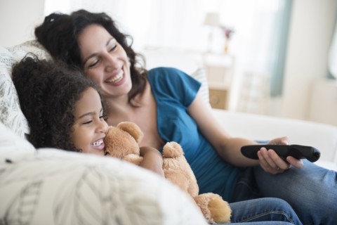 Mother and daughter watching television on sofa