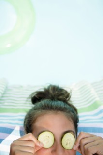 Caucasian woman with cucumbers on eyes