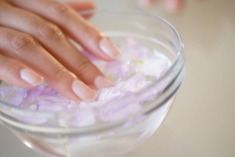 Close up of Hispanic woman soaking her nails