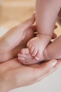 Close up of mother holding bare feet of baby