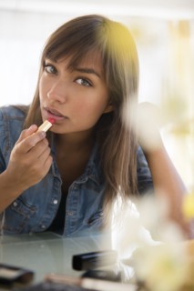 Mixed race woman applying lipstick