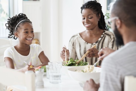 Black family eating salad at table