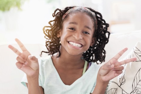 Smiling Black girl making peace sign