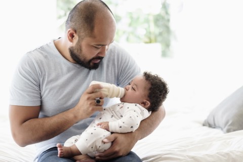 Father bottle feeding baby son