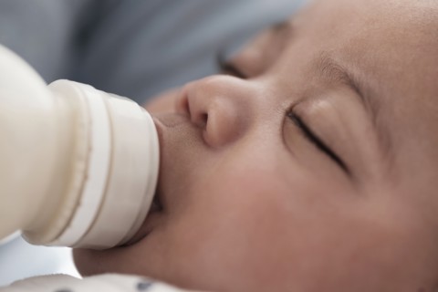 Close up of mixed race boy bottle feeding
