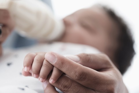 Close up of father holding hand of baby son