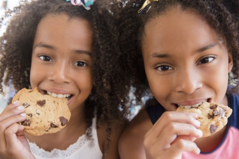 Mixed race sisters eating cookies