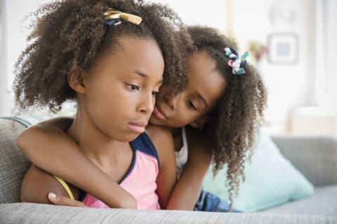 Mixed race sisters hugging on sofa