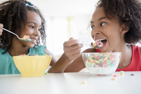 Mixed race sisters eating cereal
