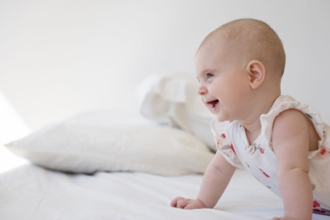 Caucasian baby girl crawling on bed