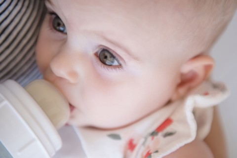 Caucasian mother feeding baby daughter