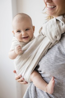 Caucasian mother holding baby daughter in sling