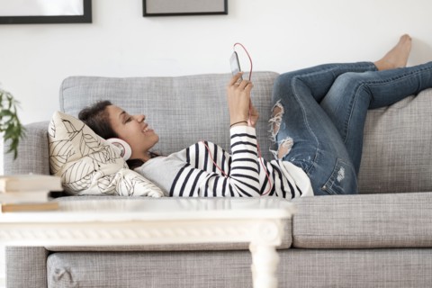 Mixed race woman listening to headphones on sofa
