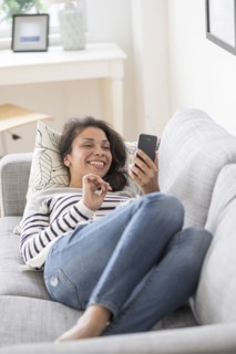 Mixed race woman using cell phone on sofa