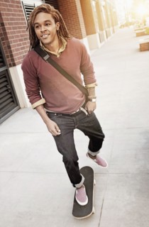 Mixed race man riding skateboard on sidewalk